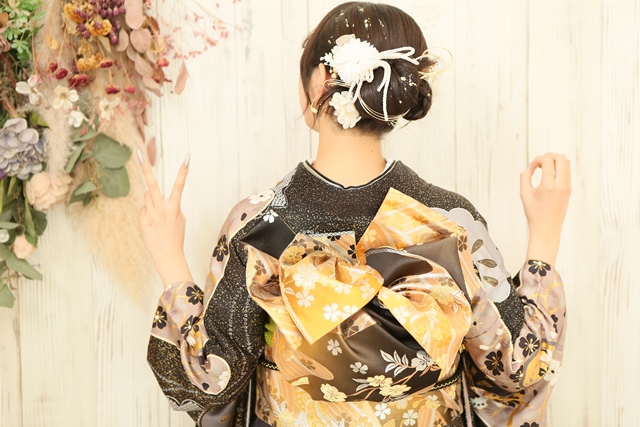 綺麗めな雰囲気の振袖にあわせてタイトヘア×金箔×水引で華やかに決めた女性
