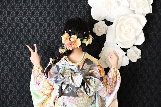 可愛らしい雰囲気の堀袖に合わせて色鮮やかな生花を使った編みおろしヘアの女性