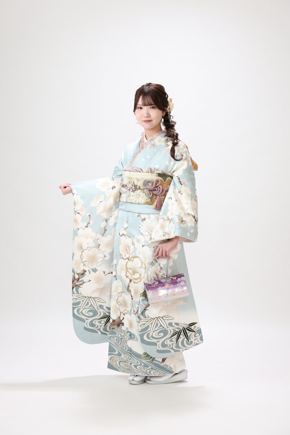 白背景で水色の振袖を着た女性が袖を広げている