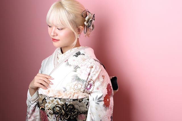 白色の振袖に黒地の帯とピンクの帯揚げを合わせた、上半身の着こなし