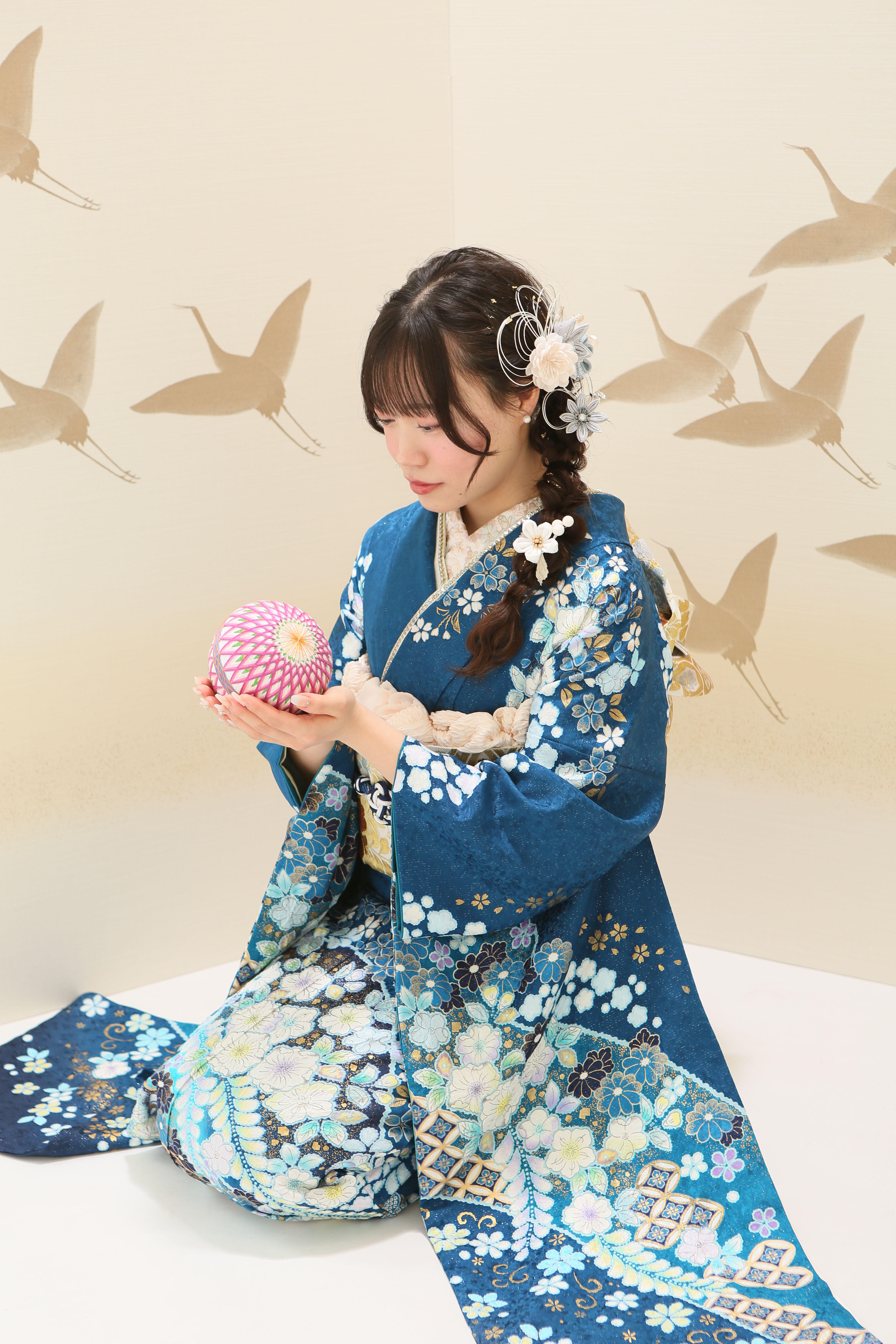辻が花の柄が入った青い振袖を着て、鞠を持つ女の子