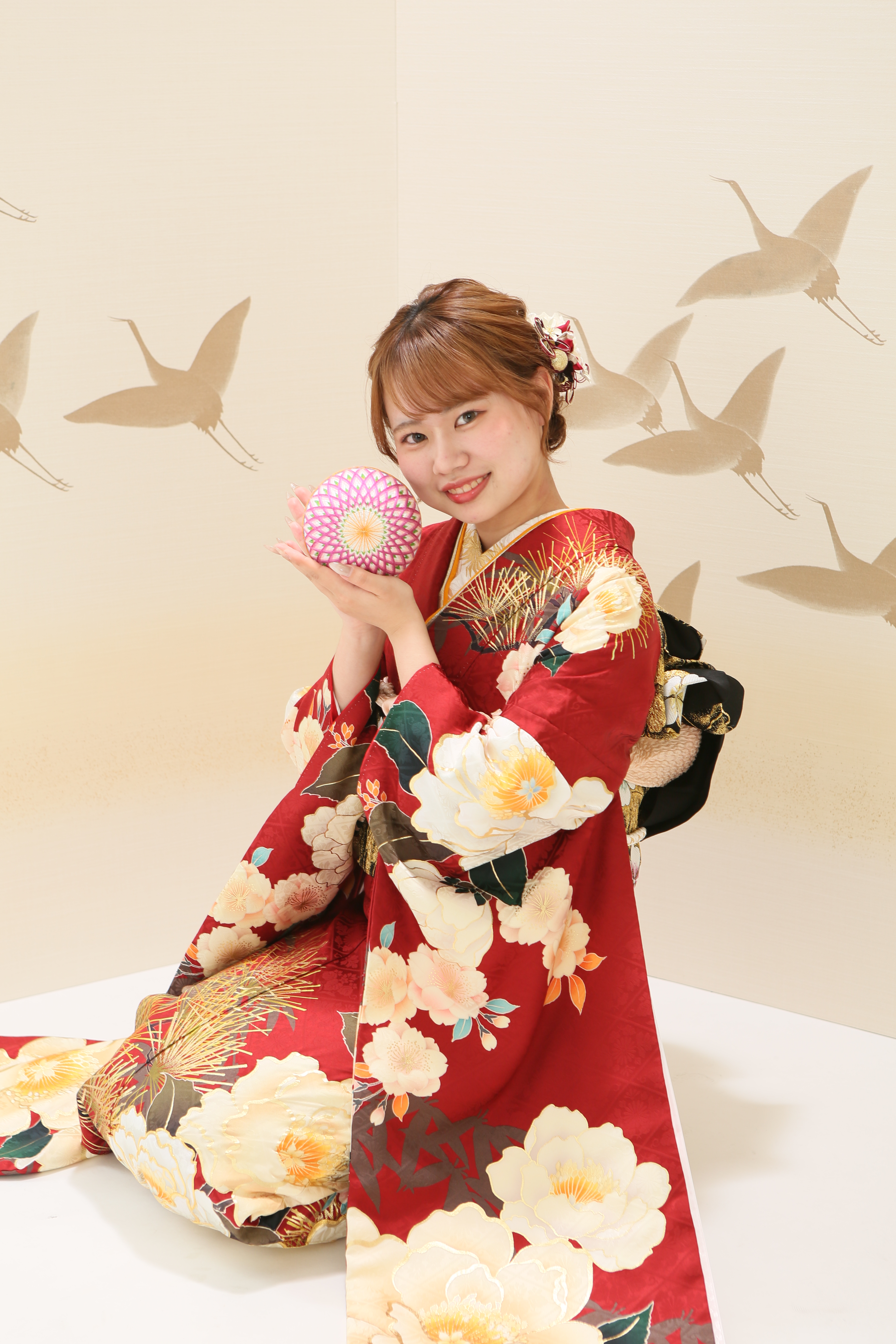 前撮り撮影で赤い振袖を着た女の子が鞠を持った写真