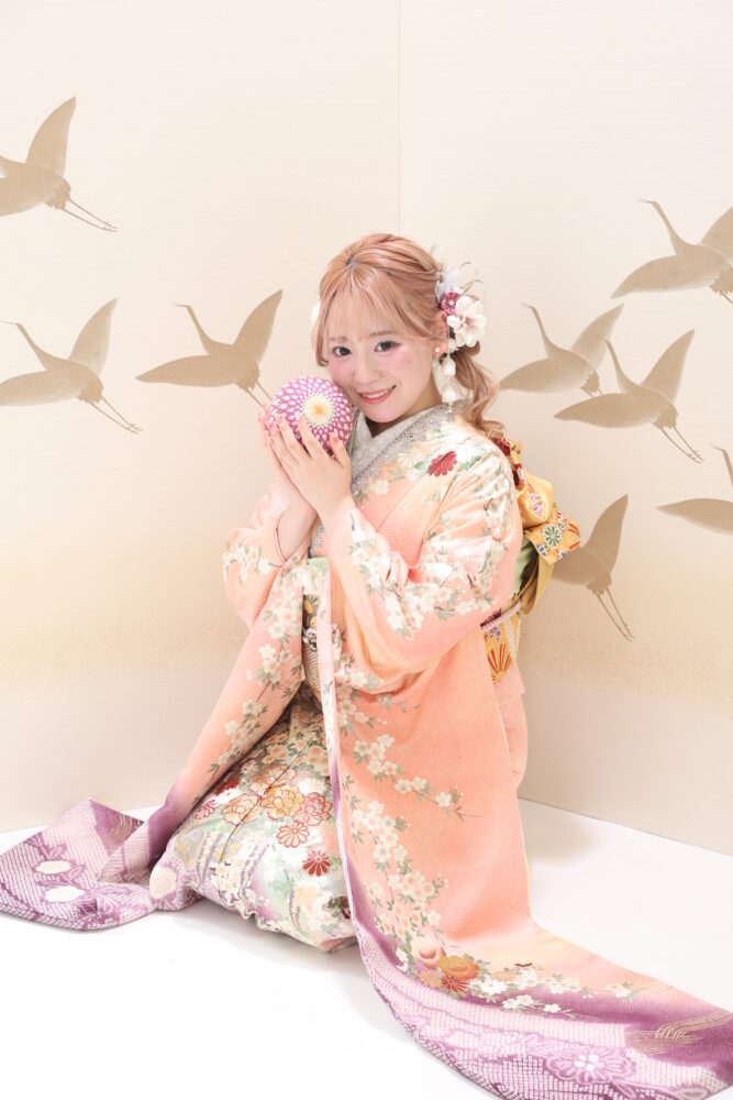 ピンク色のママ振りを着た女の子が鞠を持った写真