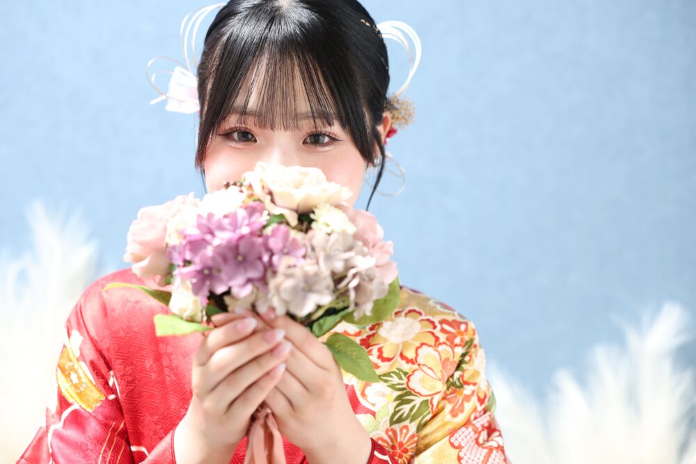 お花を持った赤い振袖のお嬢様のアップ写真